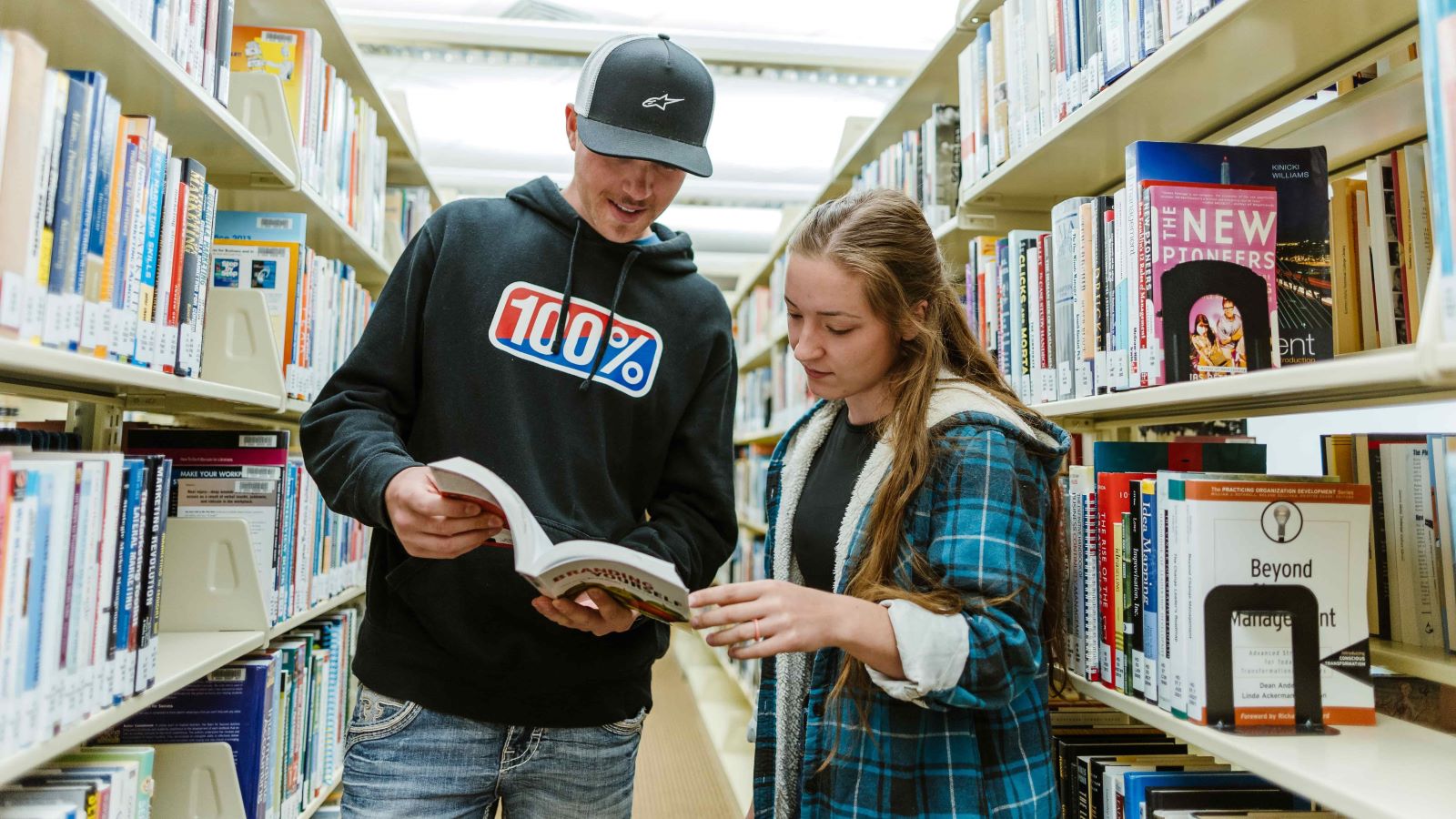 two students in library looking at book