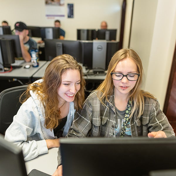 two woman on a computer, smiling