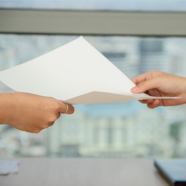 Person handing document to another individual