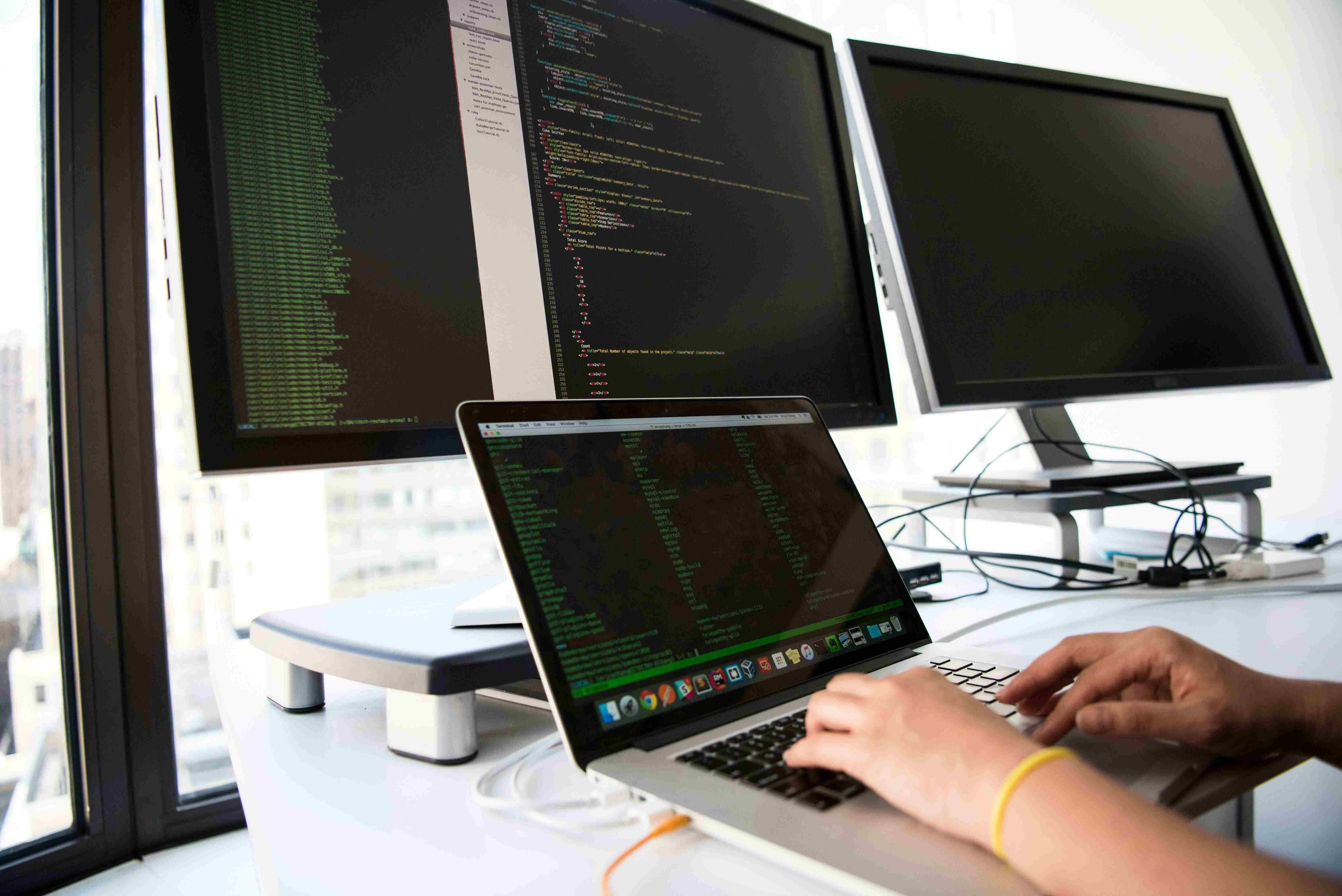 Man using a laptop with additional monitors
