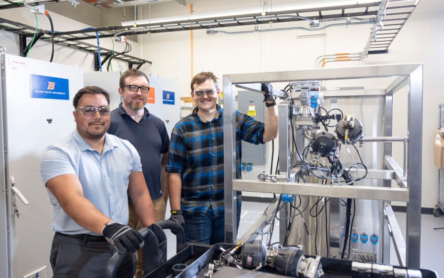 Workers pose for a photo near scientific machinery