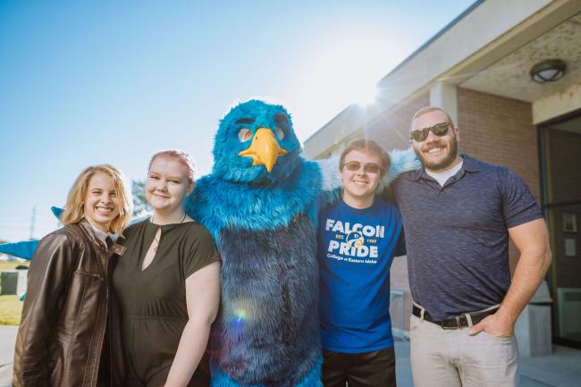 Photo of frankie the falcon with students and advisor